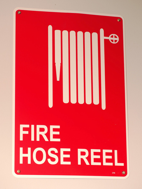 Vermelho no sinal de carretel de mangueira de fogo branco em uma parede
 - Foto, Imagem