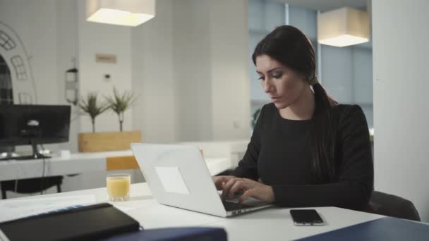 eine Frau, die am Computer arbeitet und Orangensaft trinkt - Filmmaterial, Video