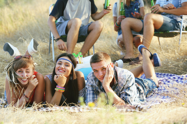 Happy smiling friends lying in the grass outdoors - Fotografie, Obrázek