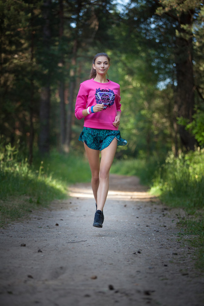 Beautiful young woman running in green park on sunny summer day - 写真・画像