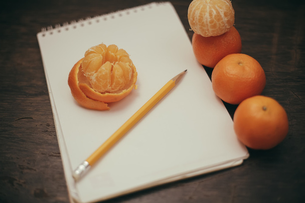 Tangerines notebook pencil coffee on old wooden background - Foto, imagen