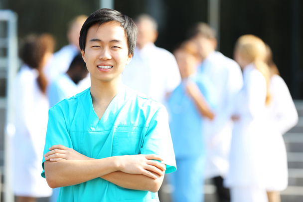 Mladý, usměvavý doktor stojící proti skupiny zdravotnických pracovníků - Fotografie, Obrázek
