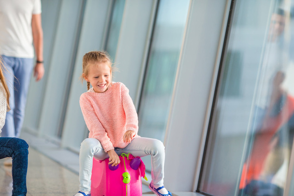 Adorable little girl having fun in airport sitting on her luggage - 写真・画像