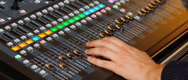 Hand of a man on Mixing Console e of a big HiFi system with many - Photo, Image