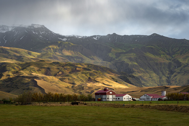 White barn with red roof in green filed surround by mountain range in Autumn season - Photo, Image