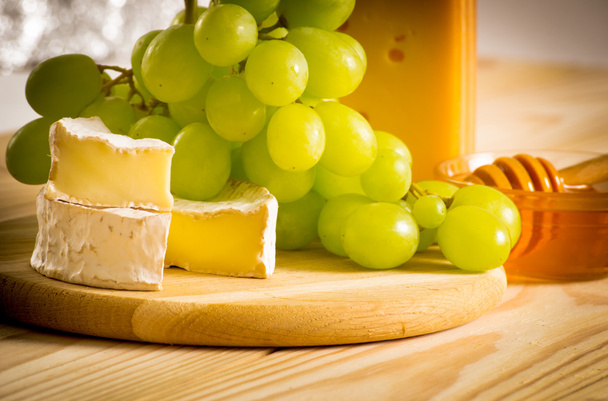 Still life of cheese, honey and grapes - 写真・画像