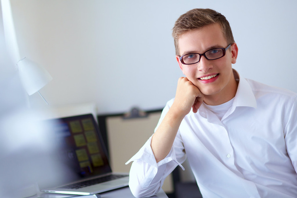 Young businessman working in office, standing near desk - Foto, afbeelding