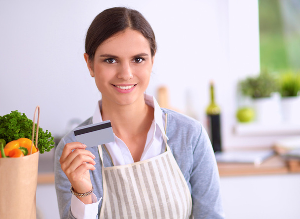 Smiling woman online shopping using computer and credit card in kitchen - Foto, immagini