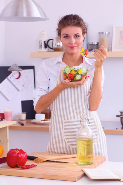 Young woman eating fresh salad in modern kitchen - 写真・画像
