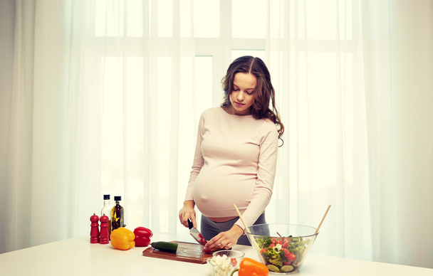 pregnant woman preparing food at home - Foto, afbeelding
