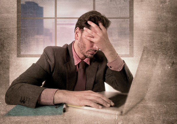 молодой привлекательный бизнесмен, сидящий за рабочим столом и работающий над компьютером ноутбук подавлен и отчаянно страдает головной болью
 - Фото, изображение