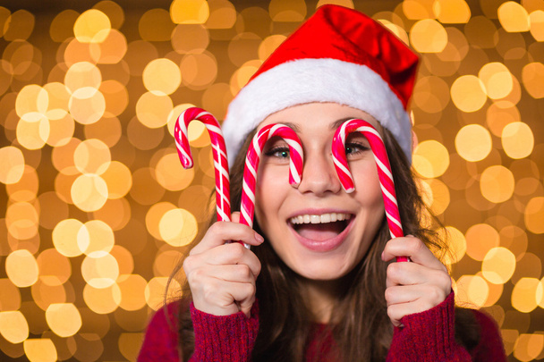 Amusing young female making funny face using christmas lollypops  - Foto, Imagem