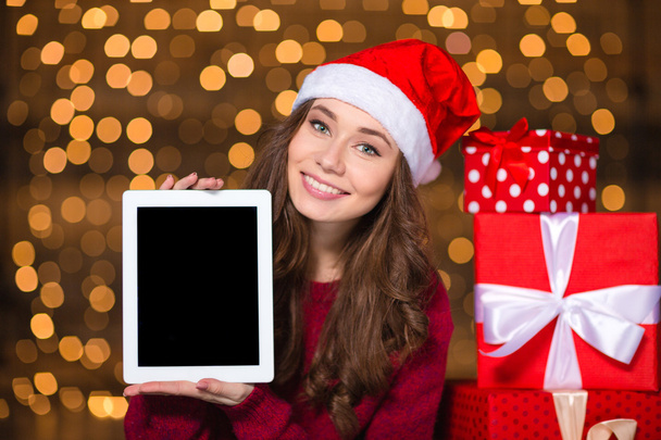 Smiling woman in santa claus hat holding tablet blank screen  - 写真・画像