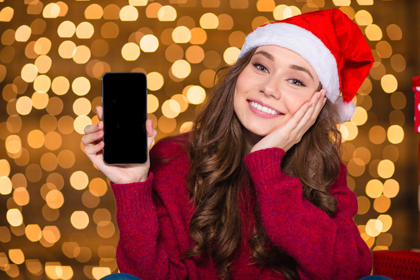 Attractive woman in santa hat holding mobile phone blank screen  - Zdjęcie, obraz