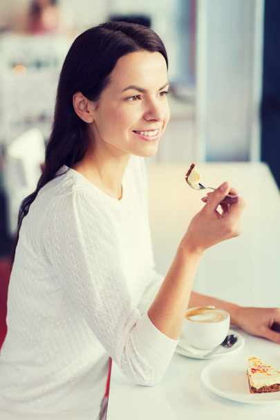 Lächelnde junge Frau mit Kuchen und Kaffee im Café - Foto, Bild