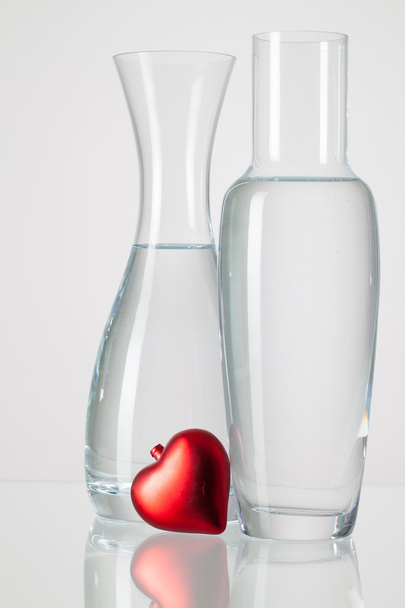 Two vases with clean water and red heart   - Foto, afbeelding