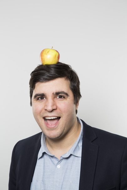 studio shot of happy person with an apple on his head - Photo, Image