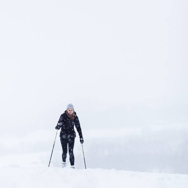 jonge vrouw cross-country skiën op een besneeuwde winterdag - Foto, afbeelding