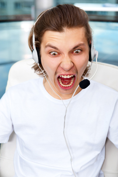 Closeup of angry screaming customer service executive or student with headphones listening online lecture - Fotó, kép