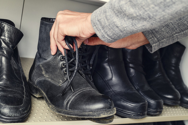 young man picking a pair of boots from the closet - Photo, Image