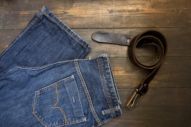 Jeans with belt on wooden background - Foto, Bild