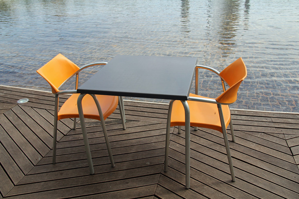 deux chaises et table dans un restaurant vide à côté de l'eau
 - Photo, image