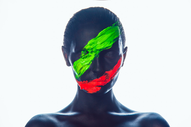 Girl with a black paint on the face. Green and red stripes. - Foto, imagen