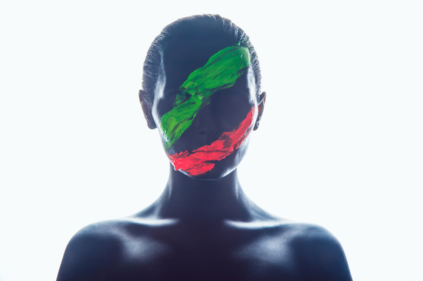 Girl with a black paint on the face. Green and red stripes. - Foto, immagini