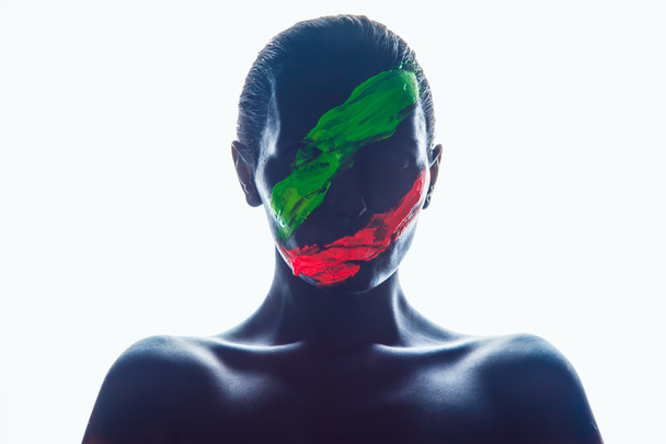 Girl with a black paint on the face. Green and red stripes. - Photo, Image