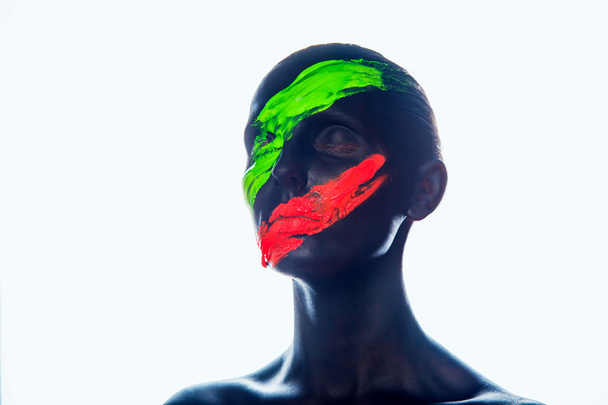 Girl with a black paint on the face. Green and red stripes. - Zdjęcie, obraz
