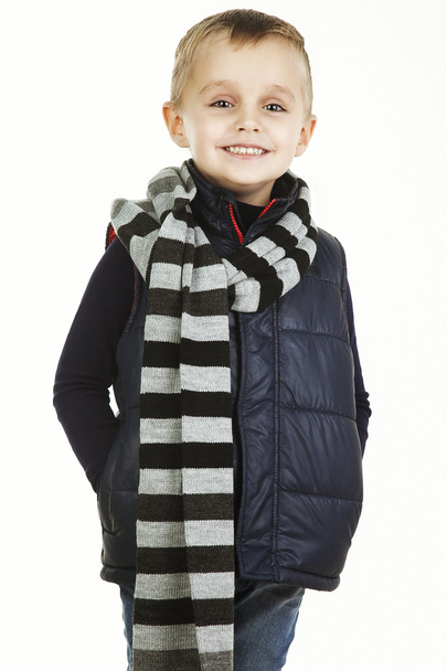 Funny child. fashionable little boy in  jeans, black shirt,  woolen  striped muffler and and padded vest .stylish  smiling  kid. fashion children - Zdjęcie, obraz