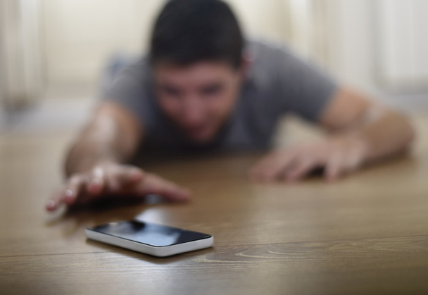 man trying to reach mobile phone creeping on the ground in smart phone and internet addiction concept - Fotoğraf, Görsel