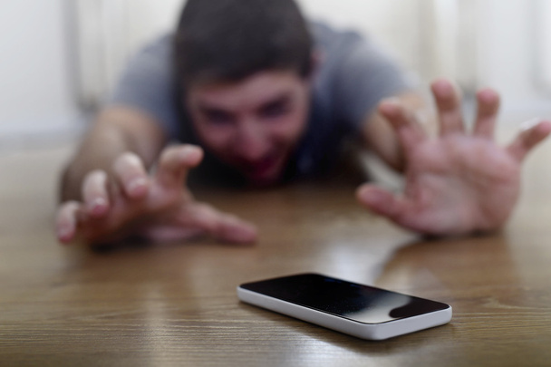 man trying to reach mobile phone creeping on the ground in smart phone and internet addiction concept - Φωτογραφία, εικόνα