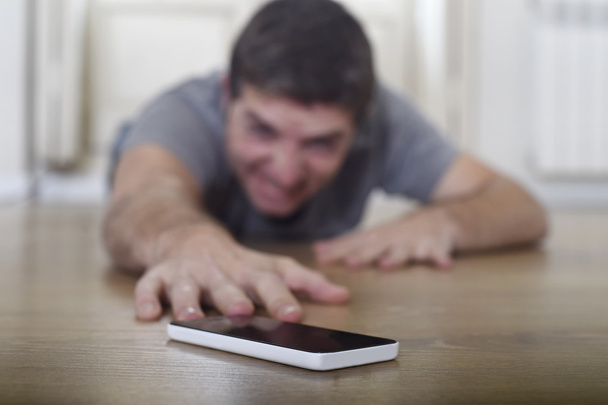 man trying to reach mobile phone creeping on the ground in smart phone and internet addiction concept - Zdjęcie, obraz
