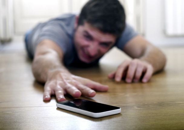 Mann versucht, in Smartphone und Internetabhängigkeit am Boden schleichend Handy zu erreichen - Foto, Bild