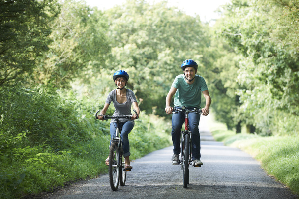 国の車線に沿ってサイクリング若いカップル - 写真・画像