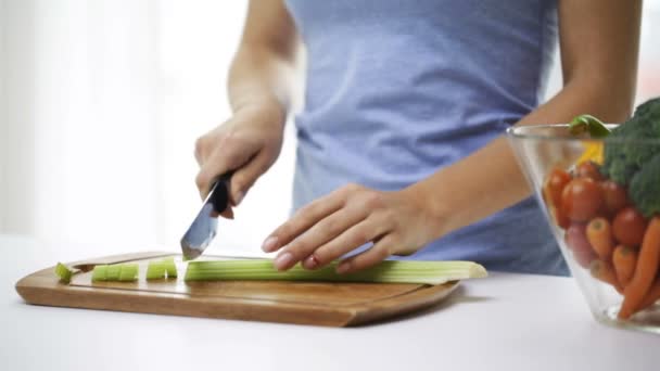 smiling young woman chopping celery at home - Filmagem, Vídeo