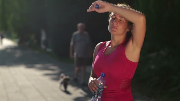 młoda kobieta picia wody po joggingu - Materiał filmowy, wideo