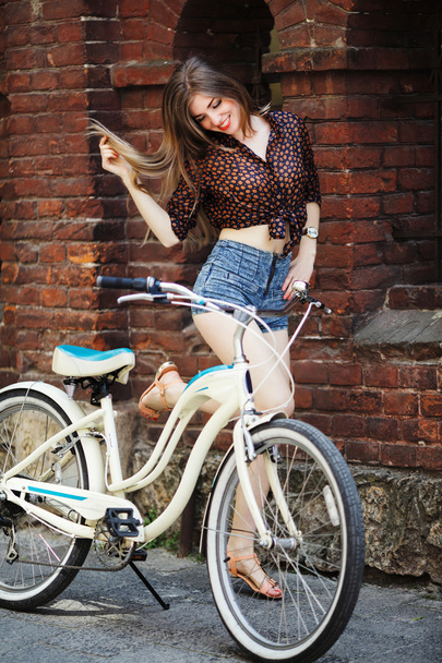 Girl with bicycle standing near wall - Foto, afbeelding
