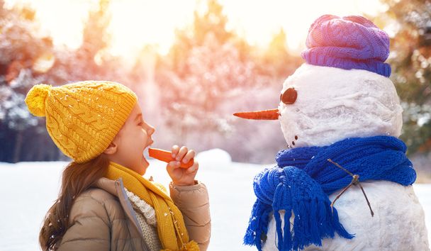 girl playing with a snowman - Fotoğraf, Görsel