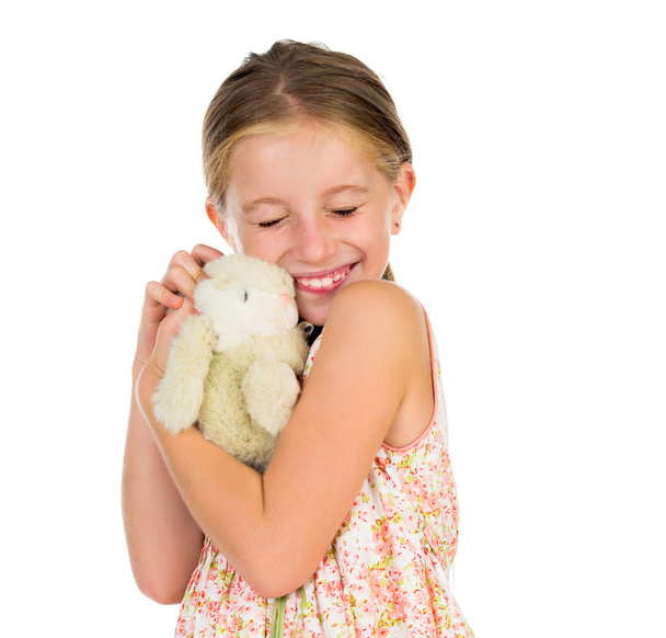 kleines Mädchen hält Spielzeughase mit zusammengekniffenen Augen - Foto, Bild