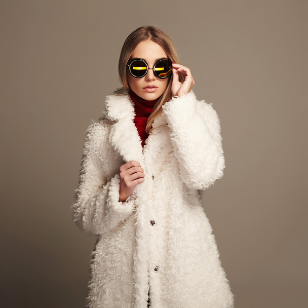 mooie winter meisje in witte vacht en zonnebril. winter - Foto, afbeelding