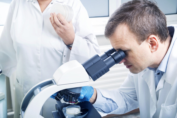 Scientist looking through microscope in laboratory - Фото, зображення