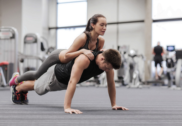 smiling couple doing push-ups in the gym - Фото, изображение