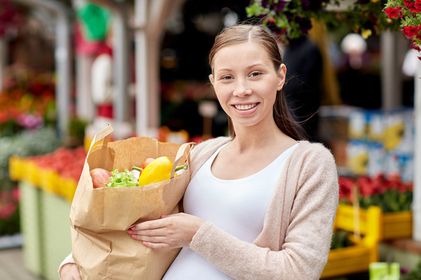 pregnant woman with bag of food at street market - Фото, изображение
