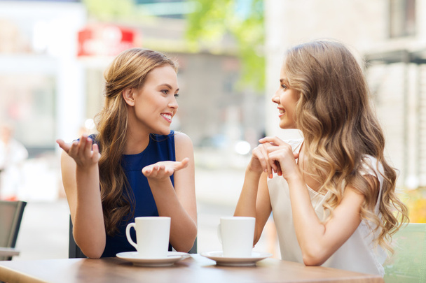 young women drinking coffee and talking at cafe - Photo, image