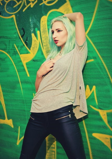 Girl posing near the wall with graffiti - Fotó, kép