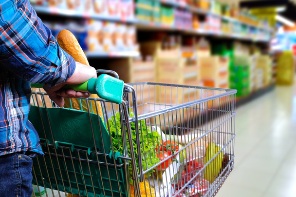 Man pushing shopping cart in the supermarket aisle - Zdjęcie, obraz