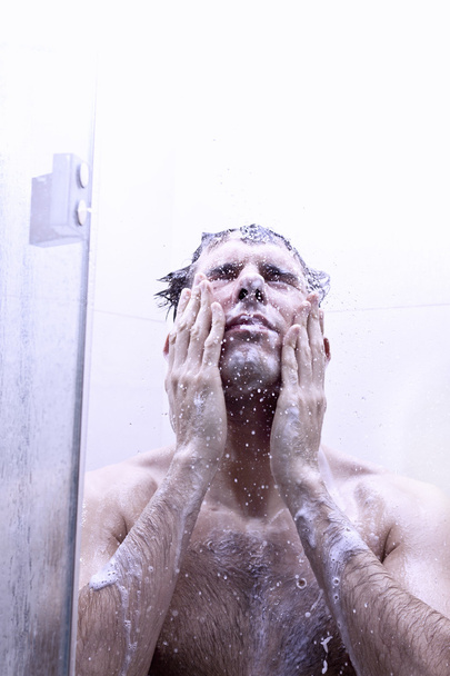Joven hombre bañándose bajo una ducha
 - Foto, imagen