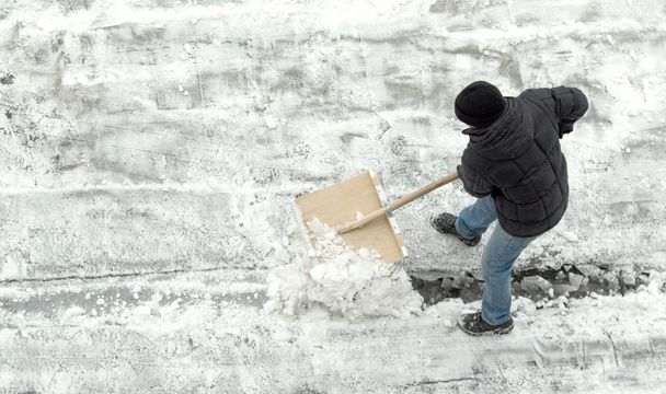 man reinigt sneeuw, bovenaanzicht - Foto, afbeelding
